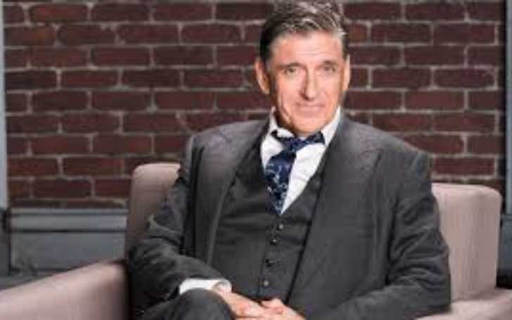 Picture of Craig Ferguson posing for a photo sitting in a chair wearing a classic suit pant.